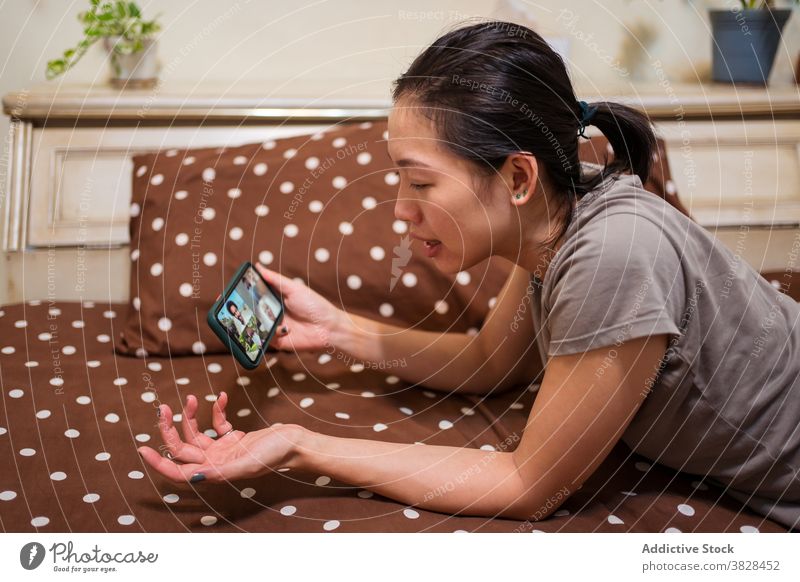 Asiatische Frau macht Videoanruf auf Smartphone zu Hause Coronavirus Selbstisolierung soziale Distanzierung Kommunizieren Video-Chat liegend online Sitzung