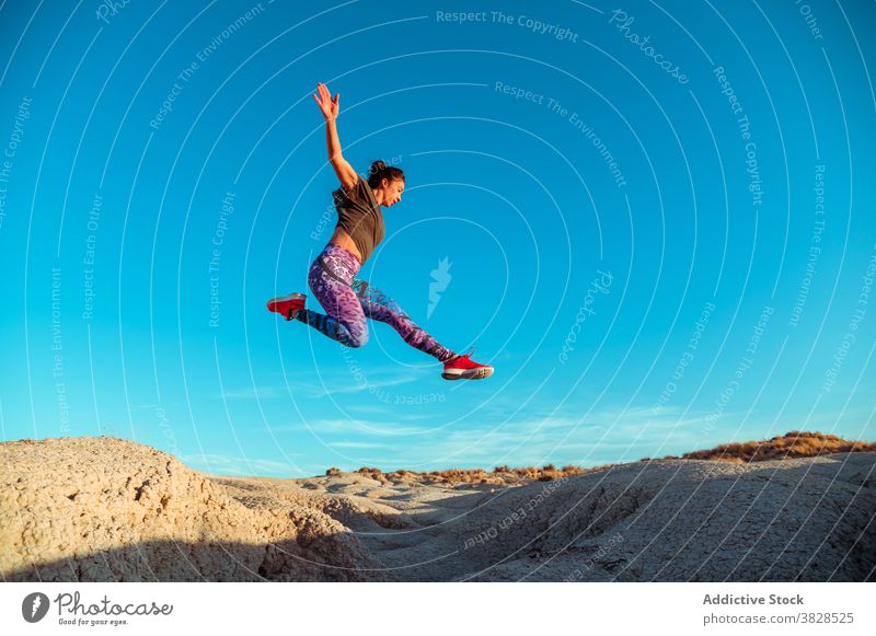 Starke Sportlerin springt über sandigen Hügel springen Fliege Skyline Blauer Himmel wüst rau aktiv Energie Sprung Athlet Frau Berghang Gelände Natur Training