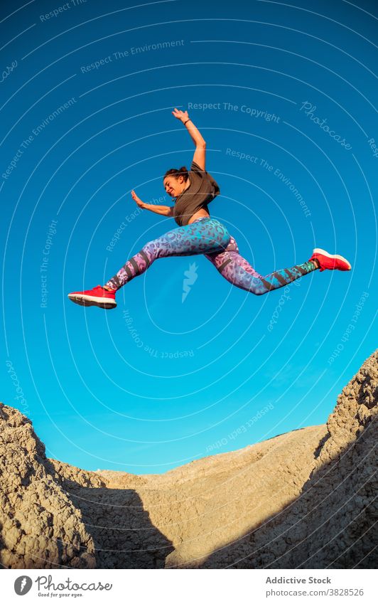 Starke Sportlerin springt über sandigen Hügel springen Fliege Skyline Blauer Himmel wüst rau aktiv Energie Sprung Athlet Frau Berghang Gelände Natur Training