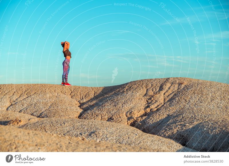 Sportliche Frau stehend auf trockenem felsigem Terrain Freiheit sportlich ausdehnen wüst trocknen Ödland allein Natur genießen meditieren Abenteuer Hügel Dürre