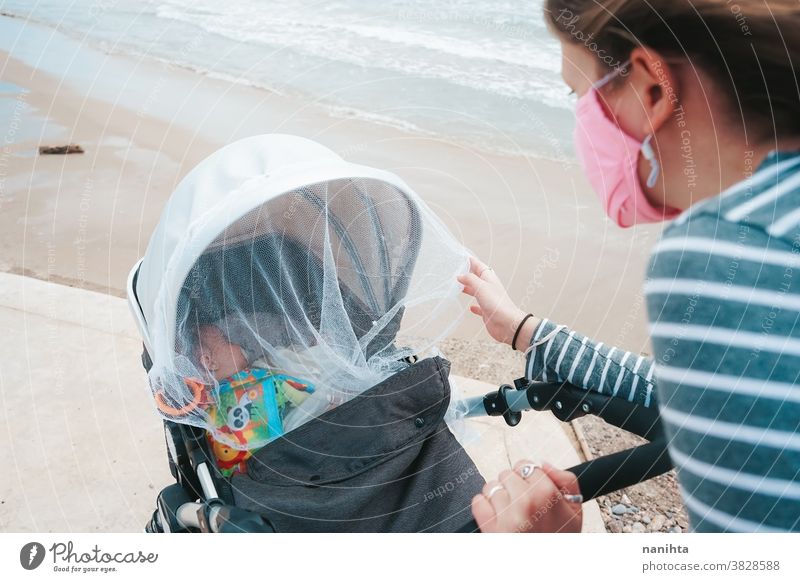 Junge Mutter geht mit ihrem Baby während einer Covid-Pandemie COVID covid-19 Coronavirus Mama Mutterschaft Familie Feiertage Mundschutz Gesichtsmaske Tochter