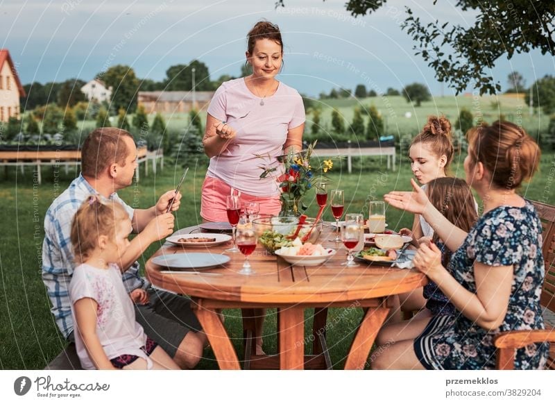 Familie isst während des Sommerpicknicks im Freien in einem Hausgarten zu Abend heimwärts Festessen habend Picknick Lebensmittel Mann Zusammensein Frau Kind