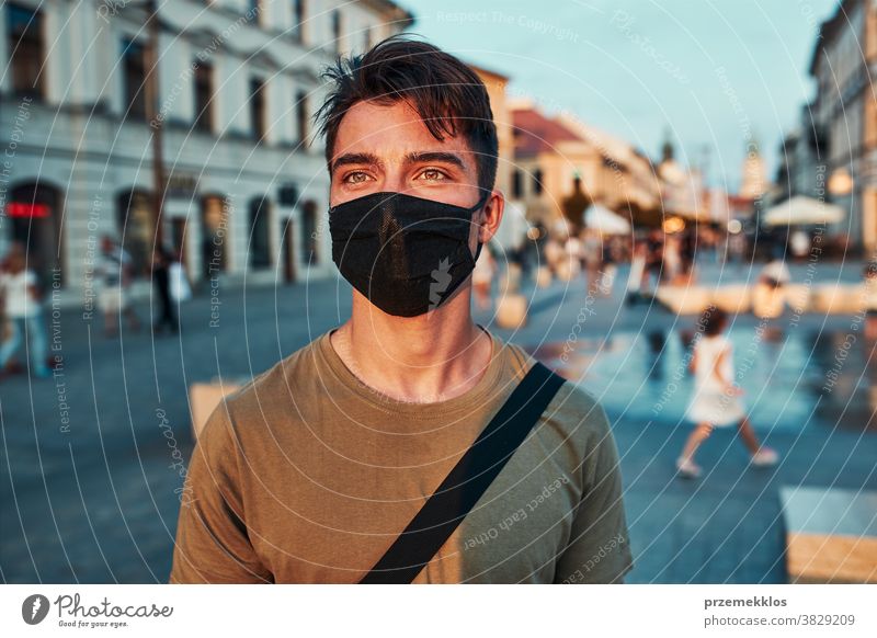 Junger Mann steht im Stadtzentrum und trägt die Gesichtsmaske, um eine Virusinfektion zu vermeiden Kaukasier Gespräch covid-19 Lifestyle Mundschutz Ausbruch