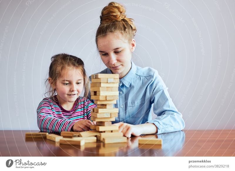 Kleines Mädchen im Vorschulalter und ihre ältere Schwester spielen zusammen mit Holzklötzen Spielzeug Aktivität Klotz Blöcke Baustein bauen Kind Kindheit
