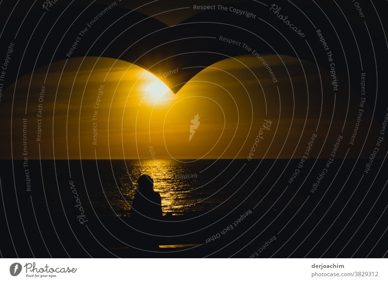 Abendsonne mit Herz, Warten auf den Sonnenuntergang am Meer. Die Struktur von einem Herzen im oberen Bild ist noch zu erkennen. Ein Schatten von einem Menschen ist zu sehen der am Ufer steht.