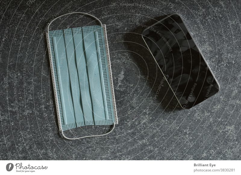Smartphone mit verschmutzter Oberfläche aufgrund von Fingerabdrücken, liegend neben der Schutzmaske Grippe Hygiene flache Verlegung Kontrolle Gerät Krankheit