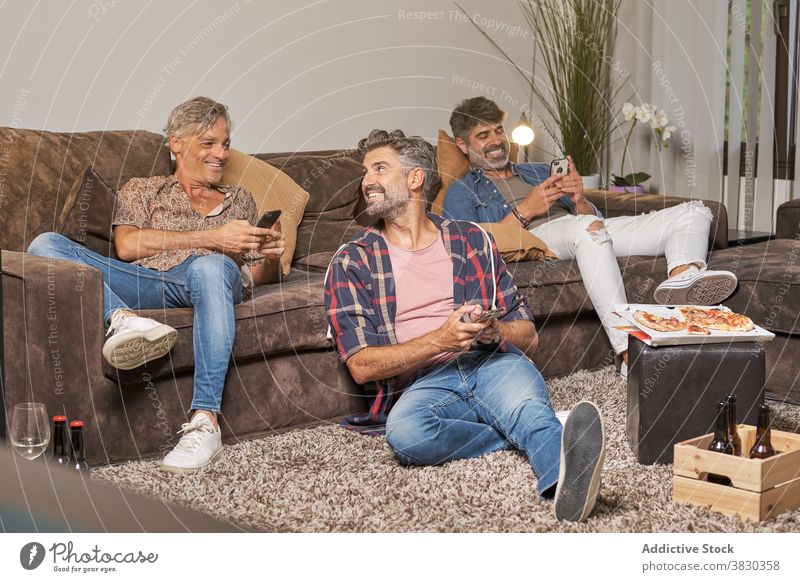 Glückliche Freunde beim Surfen auf dem Smartphone, während sie eine Pizza-Party feiern Männer Browsen heiter Freizeit räkeln Kälte Wohnzimmer Spaß
