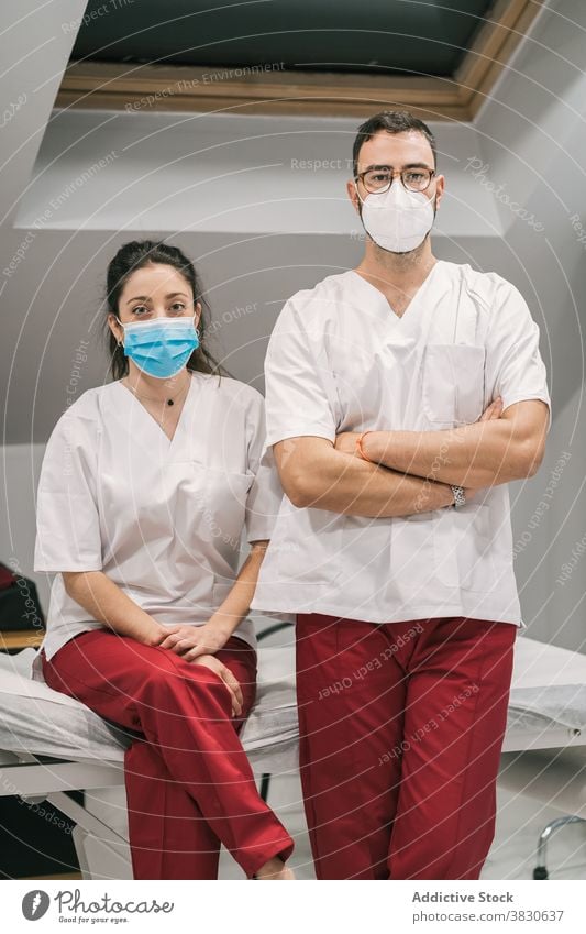Lächelnde Ärzte in Uniform und Maske schauen in die Kamera Arzt Sanitäter Krankenhaus Personal heiter Beruf Spezialist professionell medizinisch stehen Dienst