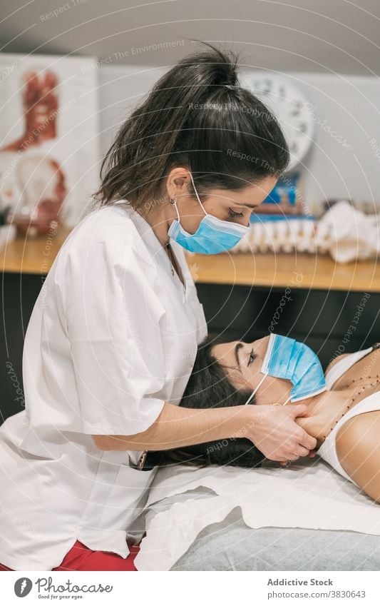 Therapeut massiert Nacken einer Patientin in Maske Physiotherapie Massage Arzt Klinik Leckerbissen professionell geduldig Hals Therapie Gesundheit