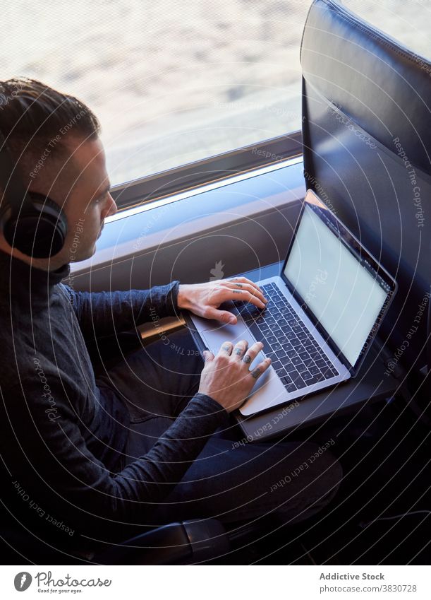 Mann mit Kopfhörern arbeitet an Laptop im Zug Business Ausflug Arbeit freiberuflich abgelegen Tippen reisen männlich Sitz modern Passagier Apparatur Gerät jung