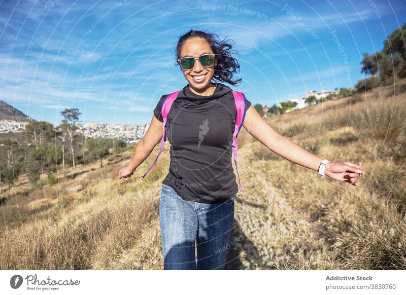 Lächelnde ethnische Frau genießt die Natur auf dem Lande Backpacker Fußweg sorgenfrei genießen sonnig Freude heiter Sonne Ausflug stehen erkunden Landschaft