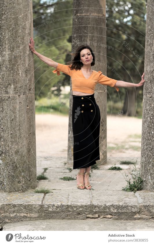 Wunderschöne Frau berührt Säulen im Park Spalte Arme auseinander nachdenklich schlanke Outfit Architektur Außenseite Top Rock Bekleidung Kleidungsstück