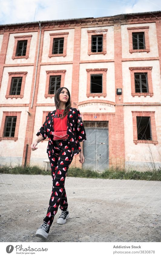 Nachdenkliche Frau zu Fuß auf dem Boden durch verlassene Konstruktion schlendern Außenseite Straße Architektur Gebäude nachdenklich Outfit Stil ernst trendy