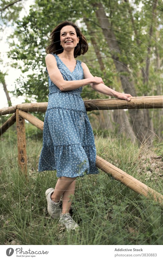 Verträumte Frau steht in der Nähe von Holzzaun auf Gehweg stehen Wald Park verträumt Stil Mode Natur Kleid Zaun dunkles Haar Vorschein nachdenken träumen trendy