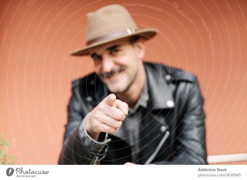Fröhlicher Mann mit Schnurrbart, der auf die Kamera zeigt heiter auf die Kamera zeigen Glück charismatisch Metrosexualität Vollbart Hut du pflücken wählen