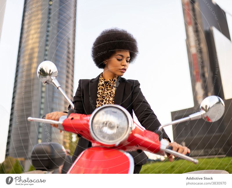 Seriöse schwarze Frau auf rotem Motorroller Motorrad altehrwürdig selbstbewusst ernst Konzentration klassisch Stil elegant nachdenklich Vorschein Individualität