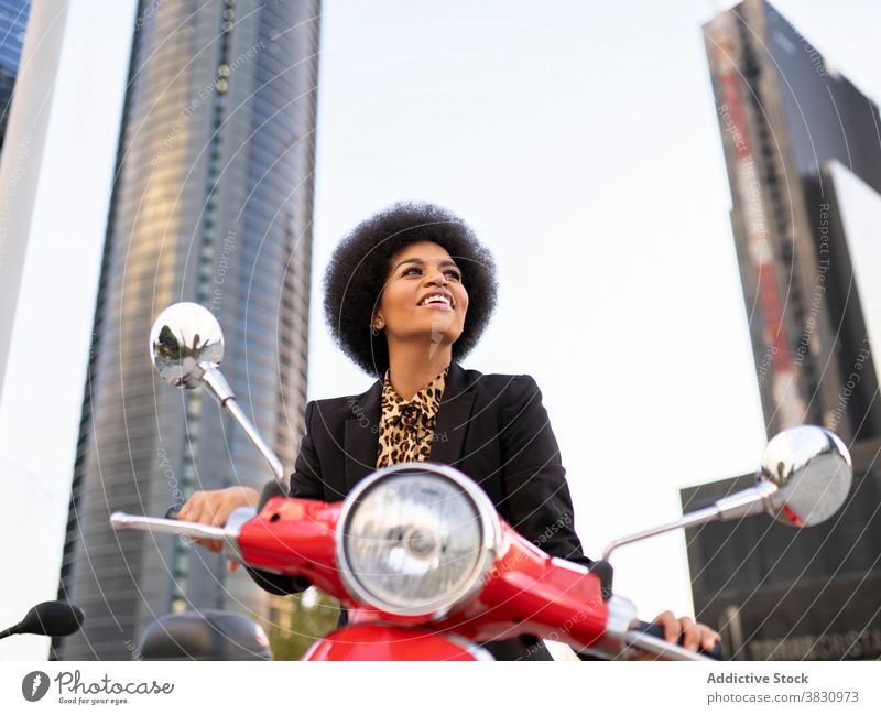 Glückliche schwarze Frau auf rotem Motorroller Motorrad altehrwürdig Lächeln selbstbewusst Freude Konzentration klassisch Stil elegant Vorschein Individualität