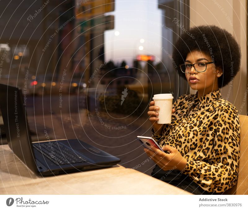 Nachdenkliche schwarze Frau mit Smartphone im Café ernst benutzend freiberuflich abgelegen selbstbewusst Internet Texten Kaffee Unternehmer Surfen Browsen Tasse