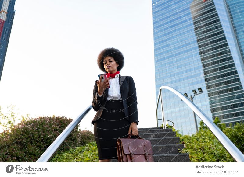 Schwarze Geschäftsfrau auf Smartphone Frau selbstbewusst Anruf benutzend Unternehmer zuhören formal Gespräch Exekutive Business Aktentasche ernst Telefon Mobile