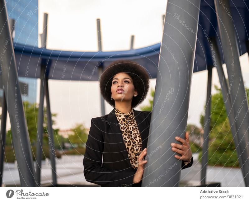 Nachdenkliche schwarze Frau lehnt an Metallpfosten verträumt selbstbewusst elegant Denken Windstille Stil friedlich ernst formal träumen Konstruktion nachdenken