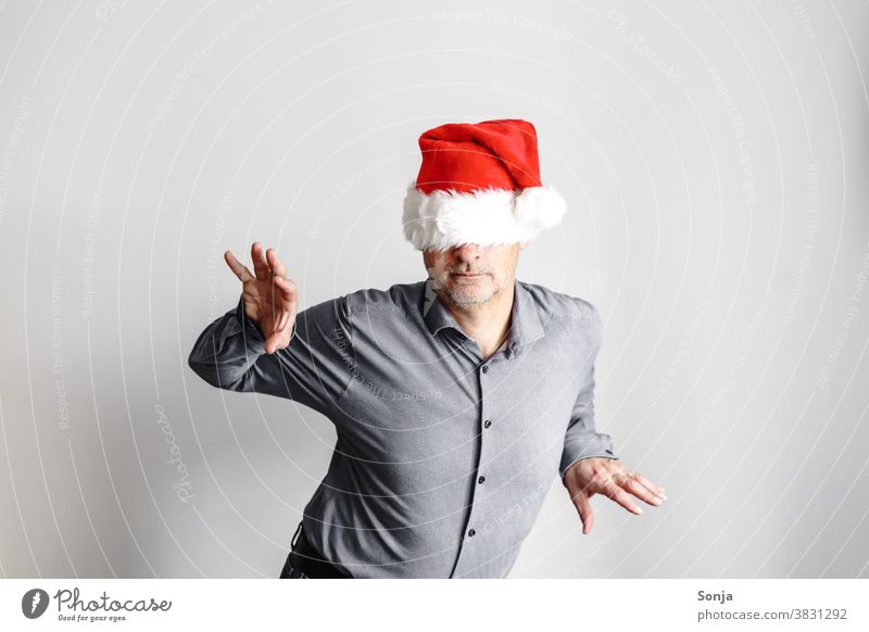 Fröhlicher Mann mit einer roten Weihnachtsmütze über den Augen Geschäftsmann fröhlich Humor lustig Porträt Freude Weihnachten Kindheit Glück Fröhlichkeit Hemd