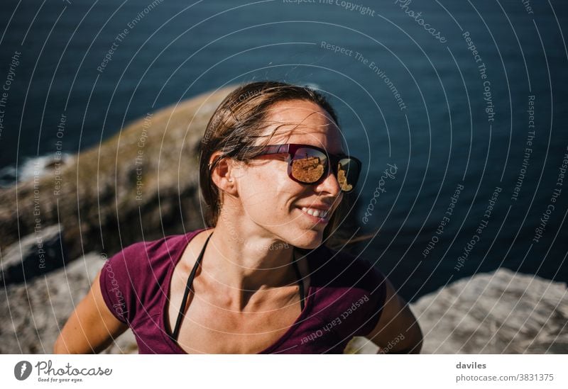 Porträt einer glücklichen natürlichen Frau mit Sonnenbrille, die sich draußen an der Küste vergnügt. Übung heiter sorgenfrei Glück sich[Akk] entspannen Stehen