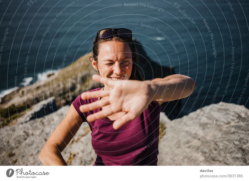 Verspielte Frau, die versucht, sich vor der Kamera des Fotografen zu verstecken, um Bilder zu vermeiden. Berge u. Gebirge MEER Natur Küste im Freien Arme Hand