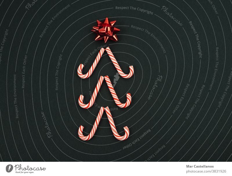 Weihnachtsbaum mit Stern aus Zuckerstangen auf schwarzem Hintergrund. Weihnachtskonzept. Dekoration & Verzierung Weihnachten Silvester u. Neujahr
