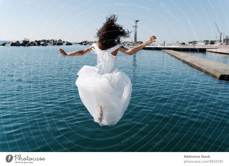 Anonyme Frau im Brautkleid fällt ins Wasser weißes Kleid hochzeitlich fallen Strandpromenade See Pier jung aufgeregt ertrinken Spaß flippig Stauanlage ängstlich