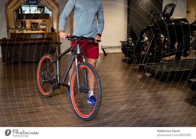 Crop-Sportler mit Fahrrad in der Turnhalle Fitnessstudio Spaziergang Training vorbereiten modern Sportbekleidung männlich Athlet passen Aktivität Ausdauer Kraft