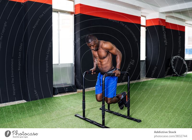 Muskulöser schwarzer Mann macht Trizepsübungen am Barren Übung Fitnessstudio Sportler parallel Athlet Training operativ männlich ethnisch Afroamerikaner Kraft