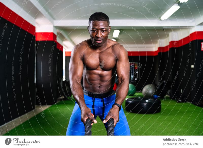 Sportler bei Übungen mit Kampfseilen Schlacht Seil operativ Training Mann Fitnessstudio Herz anstrengen stark männlich ethnisch schwarz Afroamerikaner Stärke
