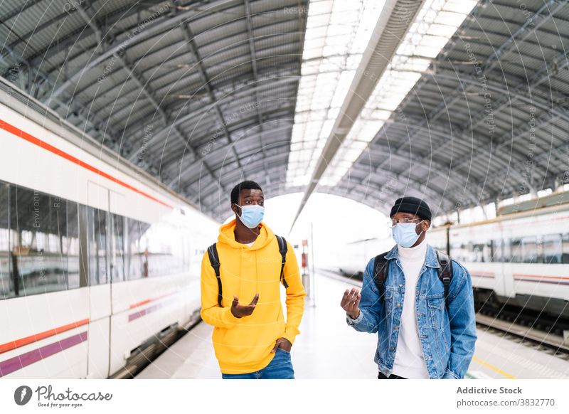 Schwarze Männer mit Masken auf dem Bahnsteig Reisender Bahnhof Podest Zug Station Zusammensein Mundschutz Coronavirus behüten ethnisch schwarz Afroamerikaner
