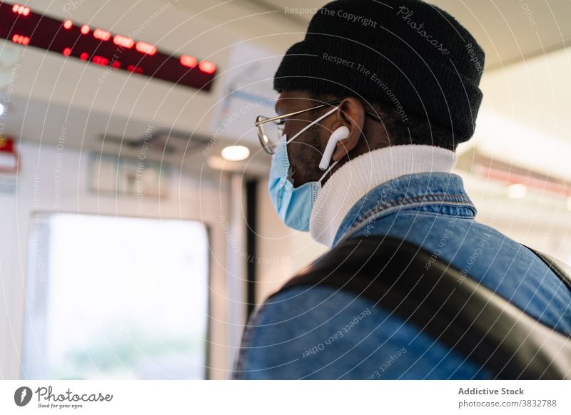 Schwarzer Mann mit Maske fährt in modernem Zug Passagier Tür Schaltfläche Reisender reisen Mundschutz Coronavirus Eisenbahn männlich ethnisch schwarz
