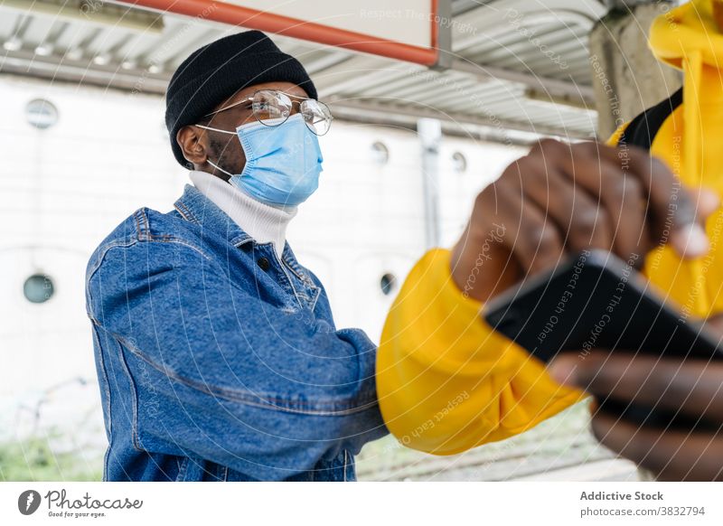 Schwarze Männer grüßen sich während der Coronavirus-Pandemie Ellbogen stoßen Gruß Freund Mundschutz Bund 19 gestikulieren neue Normale ethnisch schwarz