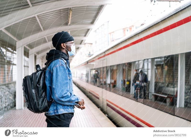 Schwarzer Mann auf Bahnsteig mit Zug Podest Eisenbahn Reisender Mundschutz Coronavirus neue Normale Tourist Station männlich ethnisch schwarz Afroamerikaner
