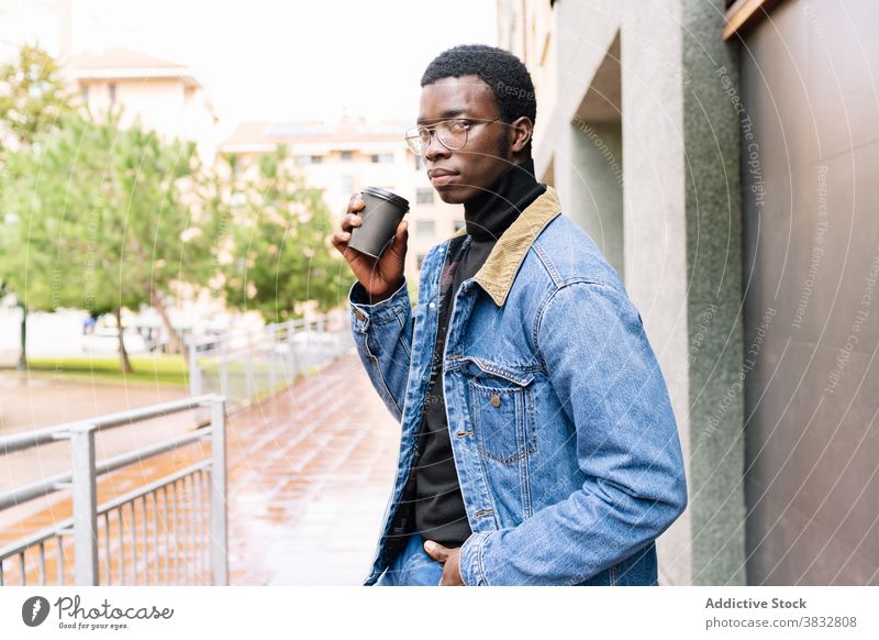 Trendiger schwarzer Mann mit Kaffee zum Mitnehmen in der Stadt Imbissbude Stil Großstadt Jeansstoff Outfit trendy trinken männlich ethnisch Afroamerikaner cool