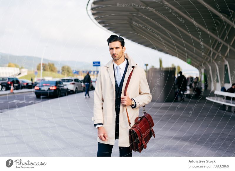 Nachdenklicher Mann schaut in die Kamera in der Nähe des Flughafens Stehen trendy zuschauen Straße Stil Geschäftsmann Konzentration männlich nachdenklich