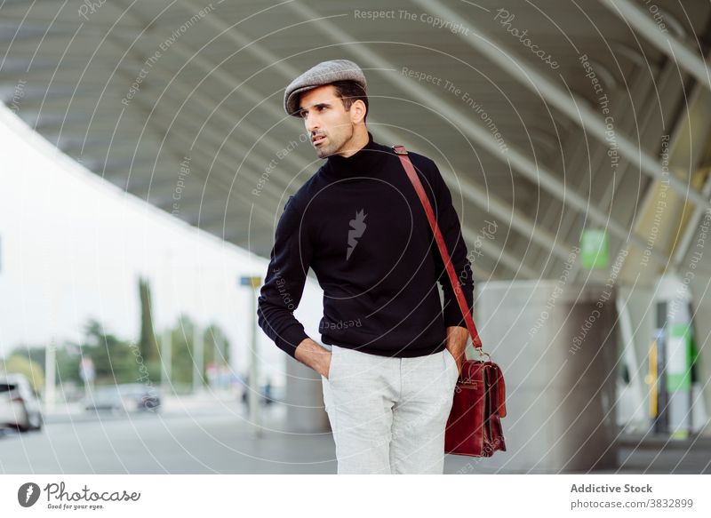 Positiver Mann zu Fuß in der Nähe des Flughafens Lächeln positiv heiter Straße Stil benutzend männlich Vollbart ethnisch trendy Asphalt geparkt tagsüber
