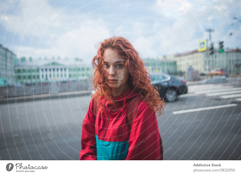 Junge rothaarige Frau steht in der Nähe der Straße in der Stadt Rotschopf rote Haare urban Großstadt jung Wind ernst tausendjährig krause Haare lange Haare