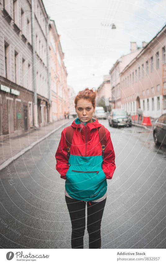 Junge rothaarige Frau steht auf der Straße in der Stadt Rotschopf rote Haare urban Großstadt jung Wind ernst tausendjährig krause Haare lange Haare