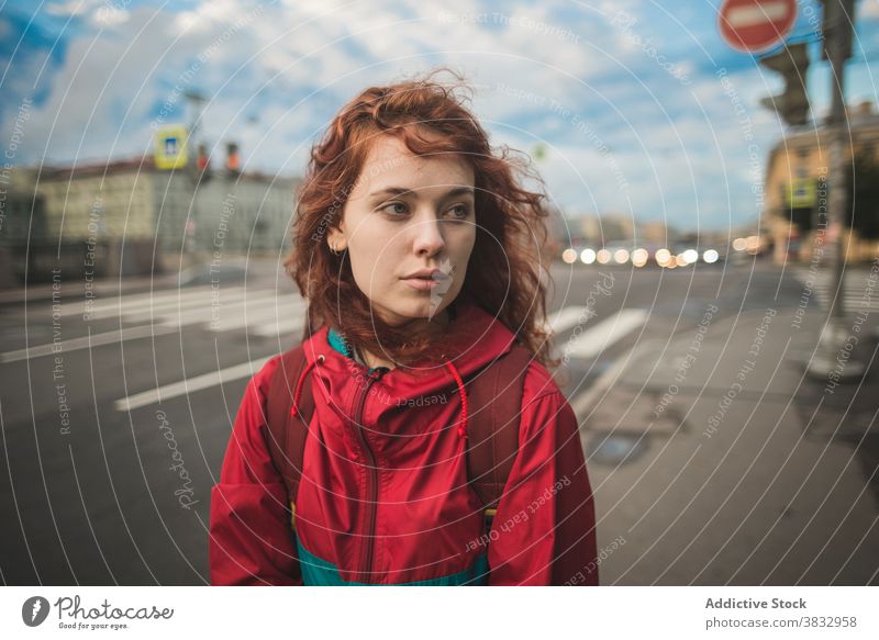 Junge rothaarige Frau steht auf der Straße in der Stadt Rotschopf rote Haare urban Großstadt jung Wind ernst tausendjährig krause Haare lange Haare