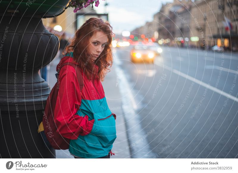 Junge rothaarige Frau steht in der Nähe der Straße in der Stadt Rotschopf rote Haare urban Großstadt jung Wind ernst tausendjährig krause Haare lange Haare