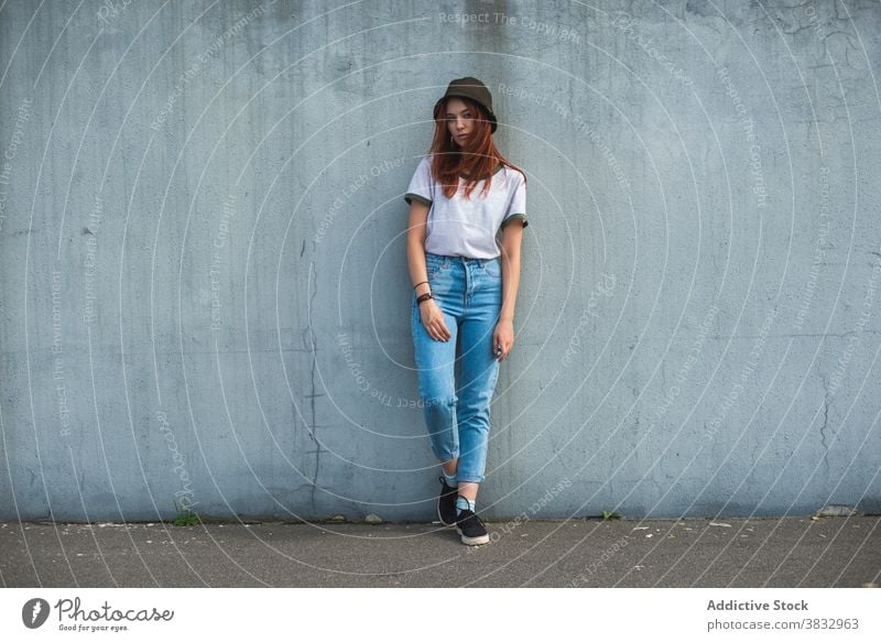 Hipster junge Frau in Hut stehend in der Nähe von Wand trendy tausendjährig urban Stil Schüler lässig Teenager rote Haare Rotschopf Outfit Mode Lifestyle