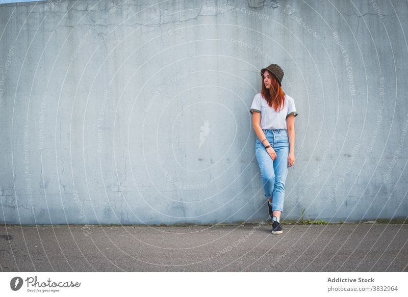 Hipster junge Frau in Hut stehend in der Nähe von Wand trendy tausendjährig urban Stil Schüler lässig Teenager rote Haare Rotschopf Outfit Mode Lifestyle