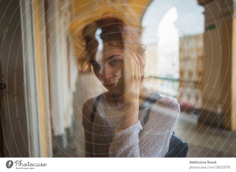 Junge Frau schaut durch das Fenster eines alten Gebäudes neugierig Rotschopf urban besinnlich reisen Reflexion & Spiegelung einsam jung Russland