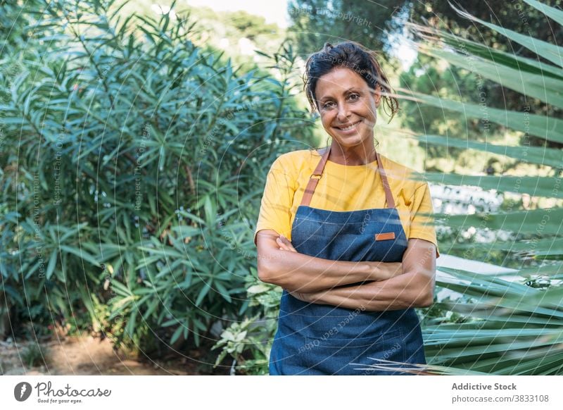 Glückliche Frau mit Harke arbeiten im Garten grün Arbeit Lächeln positiv Sommer heiter Erwachsener ethnisch Natur Pflanze Beruf Gärtner ländlich Landschaft