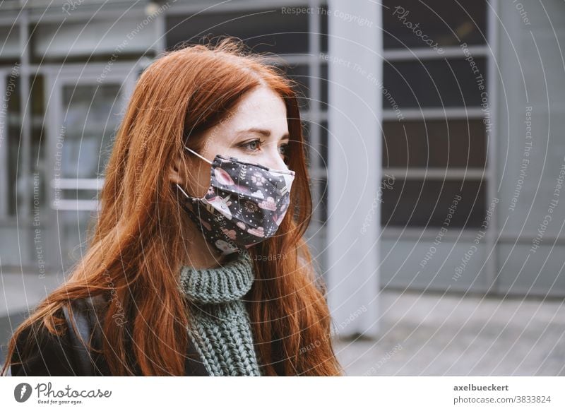 junge Frau, die draußen in der Stadt eine selbstgemachte Alltagsmaske aus Stoff trägt Mund-Nasen-Bedeckung Mundschutz Coronavirus covid-19 Lifestyle Winter