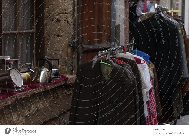 Flohmarktartikel vor einem Gebrauchtwarenladen. Antiquitäten Kleidung gebraucht geschäft verkauf kleiderstange fenster Ware trachtenjacke waage kanne Handel