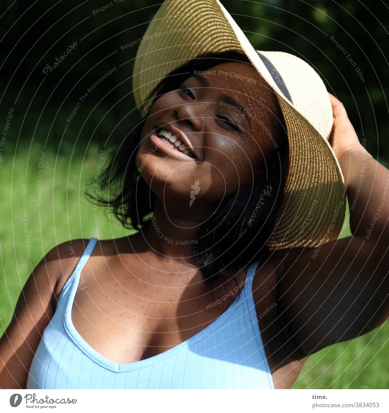 lachende Frau mit Strohhut frau schwarzhaarig t-shirt sonnig sommer schatten lächeln gute laune fröhlich